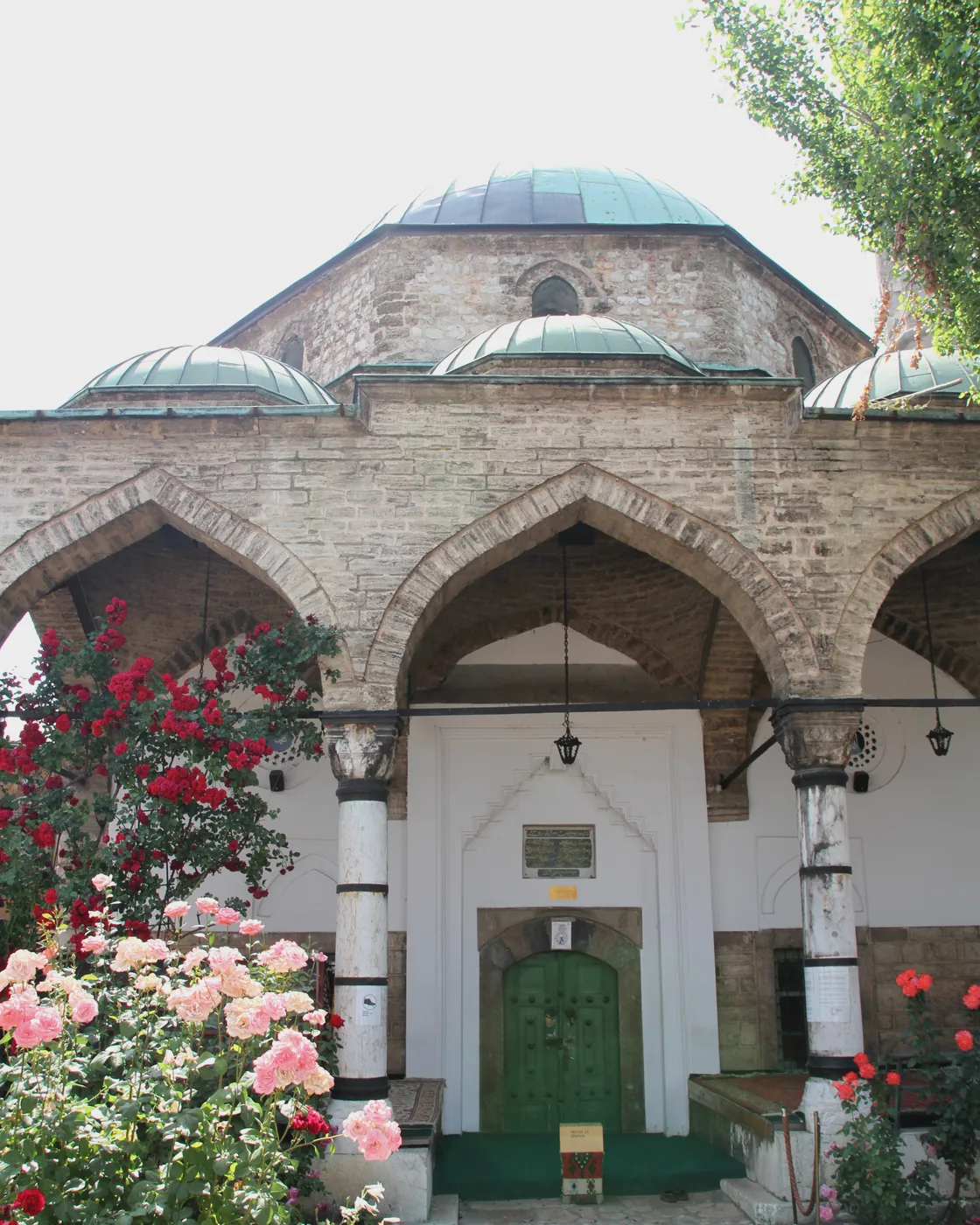 The domes and arcaded courtyard of the Gazi Husrev-beg mosque, Sarajevo, roses in the foreground